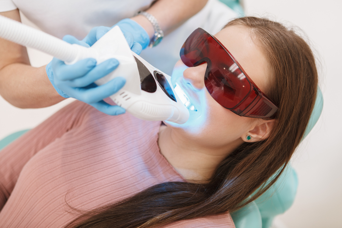 Woman getting teeth whitening by professional dentist